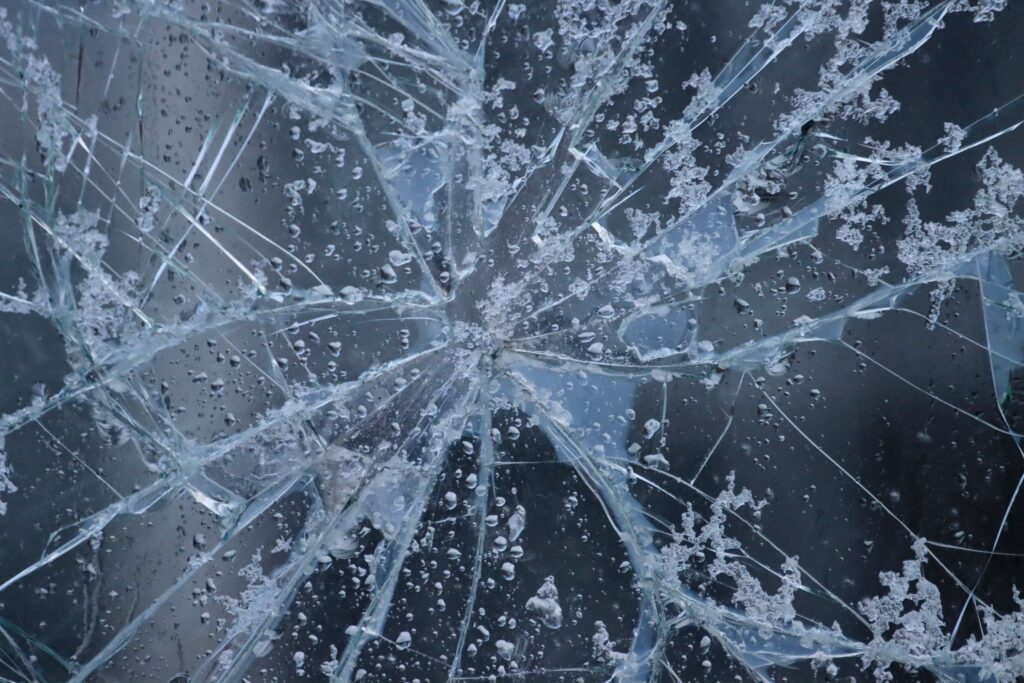 現在の画像: A close-up view of shattered glass with frost and water droplets, evoking winter in Sweden.