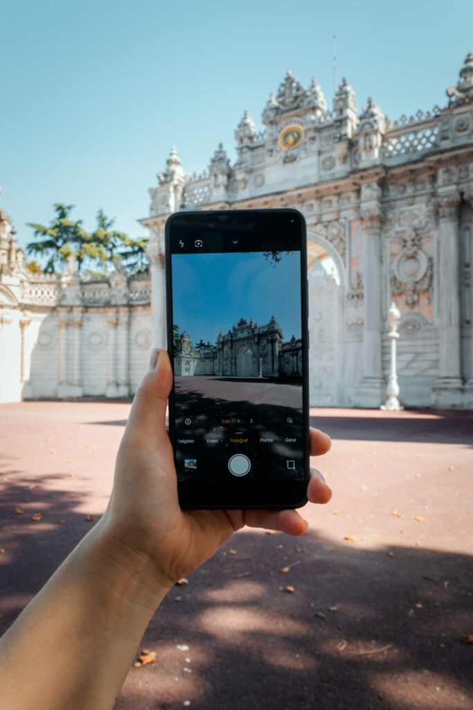 現在の画像: A person holds a smartphone photographing Dolmabahçe Palace Gate in İstanbul, Türkiye.