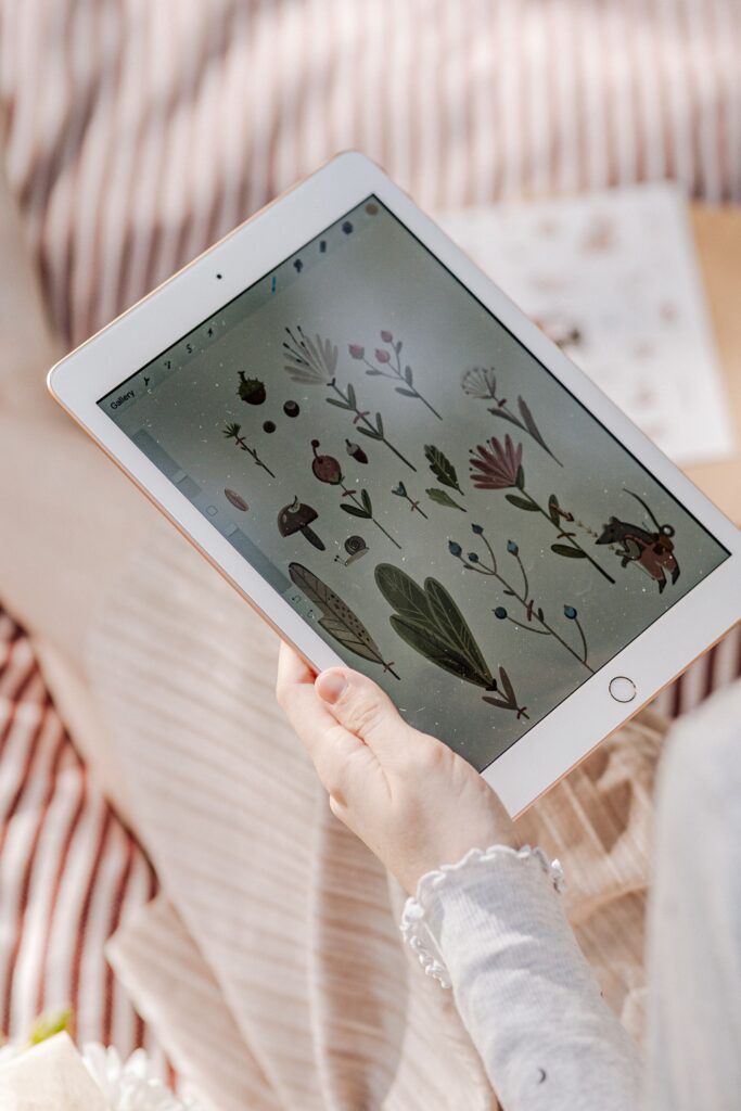 現在の画像: A person sketching floral illustrations on a tablet, showcasing digital art and technology integration.