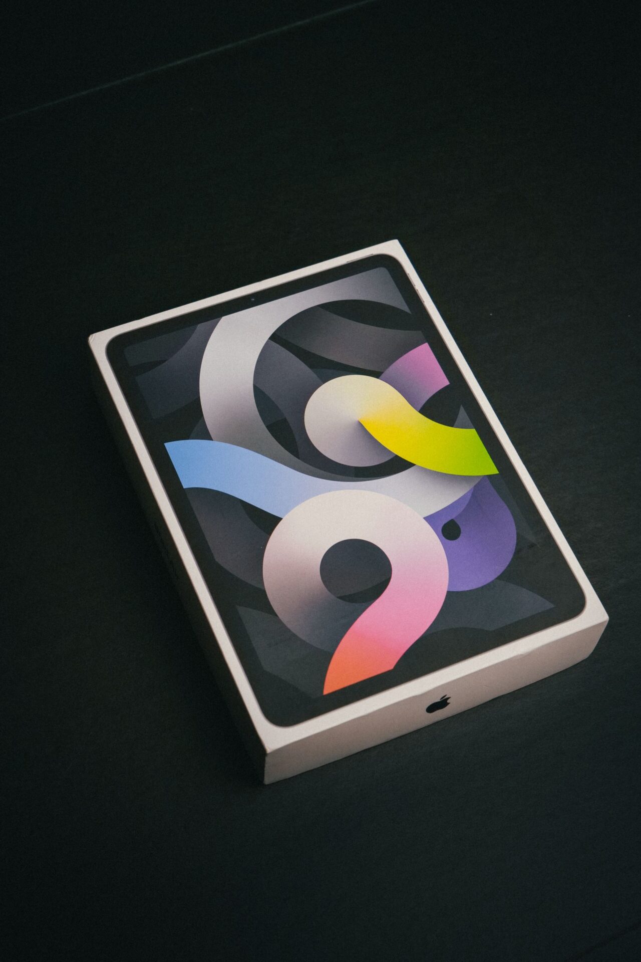 A vibrant tablet packaging box showcasing colorful abstract design on a dark surface.