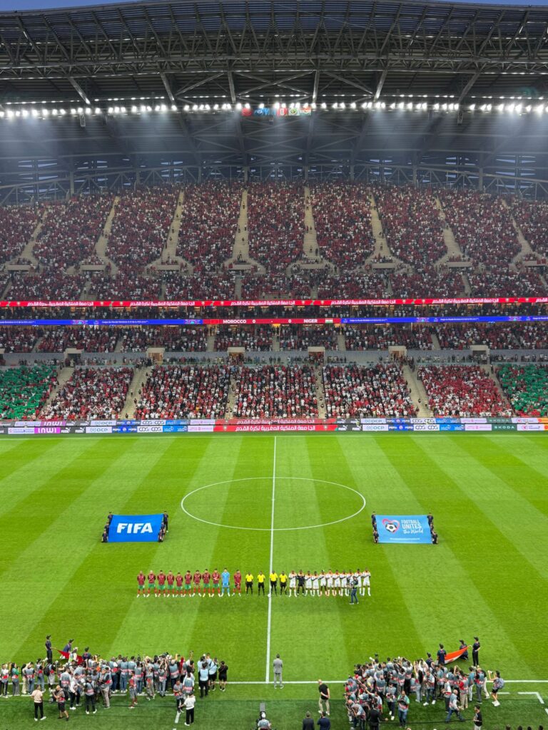 現在の画像: Aerial view of a football match kickoff in a vibrant, full stadium.