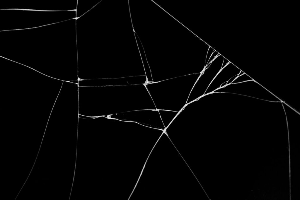 現在の画像: An abstract depiction of broken glass with a stark black background, symbolizing fragility.