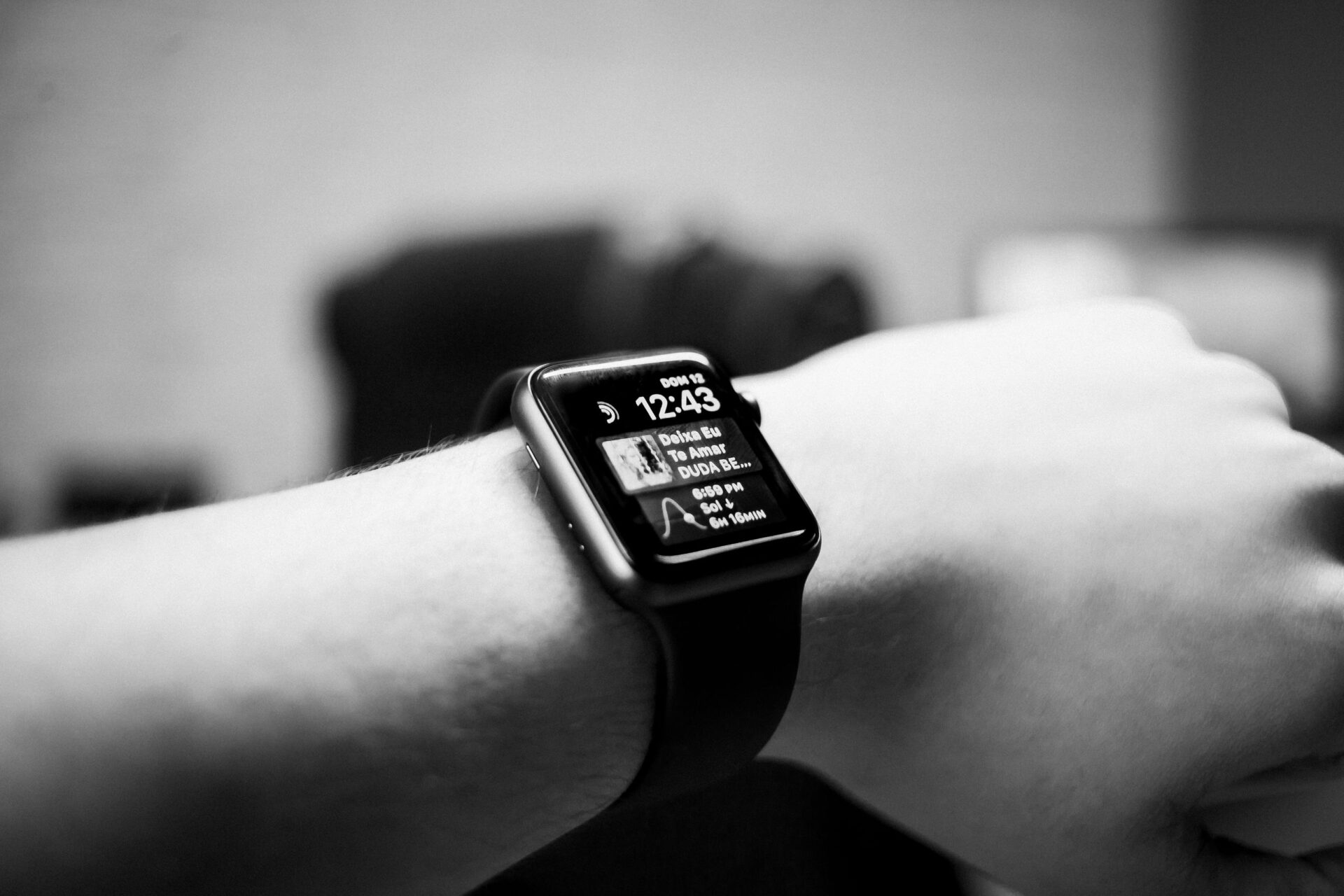 Black and white close-up of a smartwatch displaying notifications on a wrist.