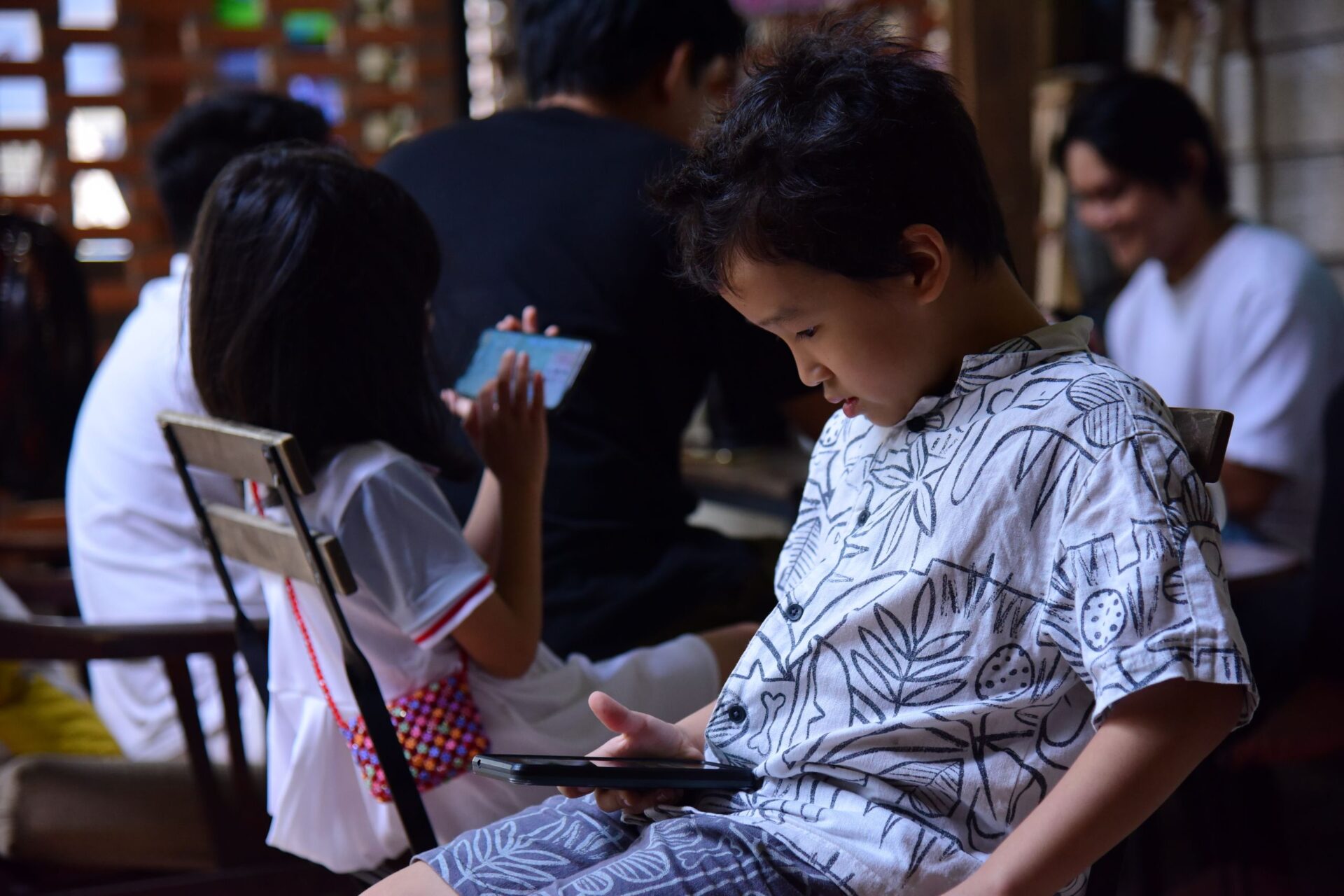 Children focused on smartphones indoors, highlighting contemporary digital lifestyle.
