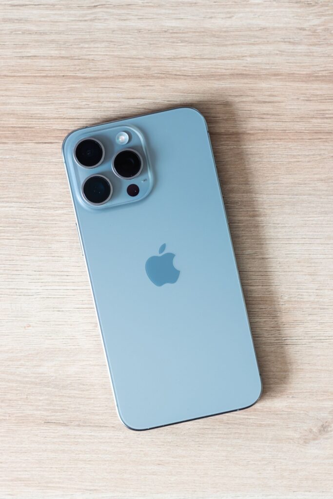 現在の画像: Close-up of a modern smartphone on a light wooden table surface.