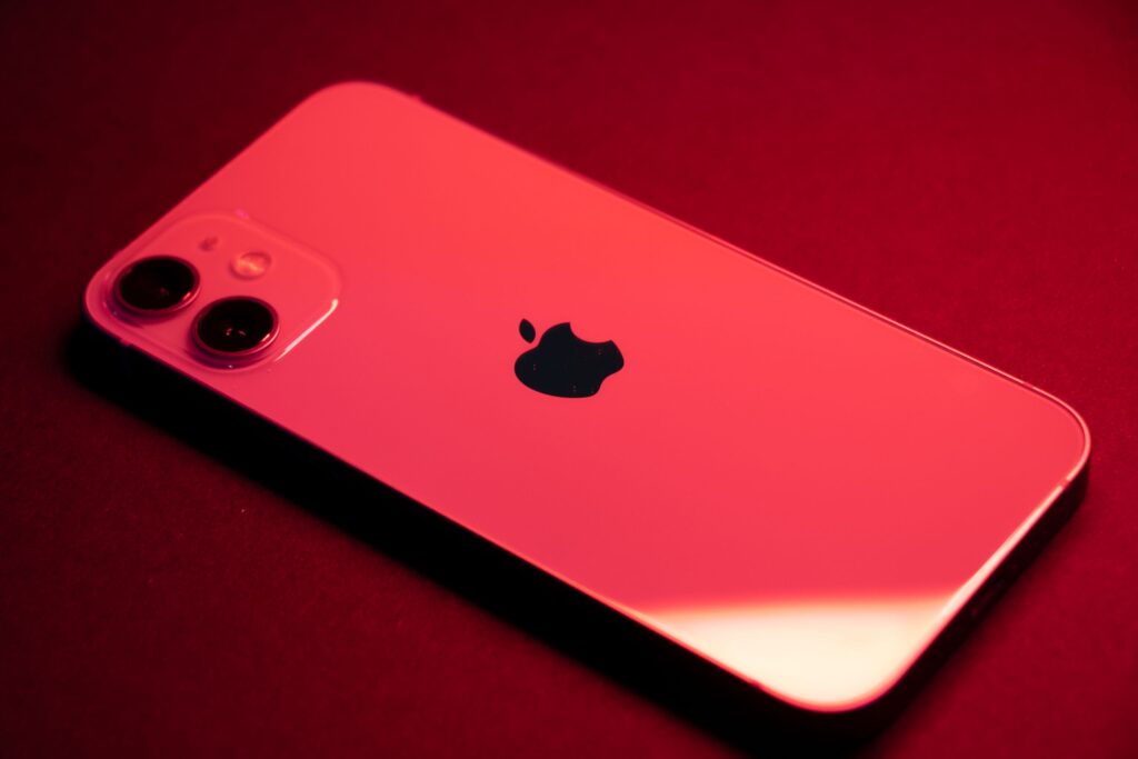 現在の画像: Close-up of a red smartphone with dual lenses on a red backdrop, highlighting sleek design and technology.