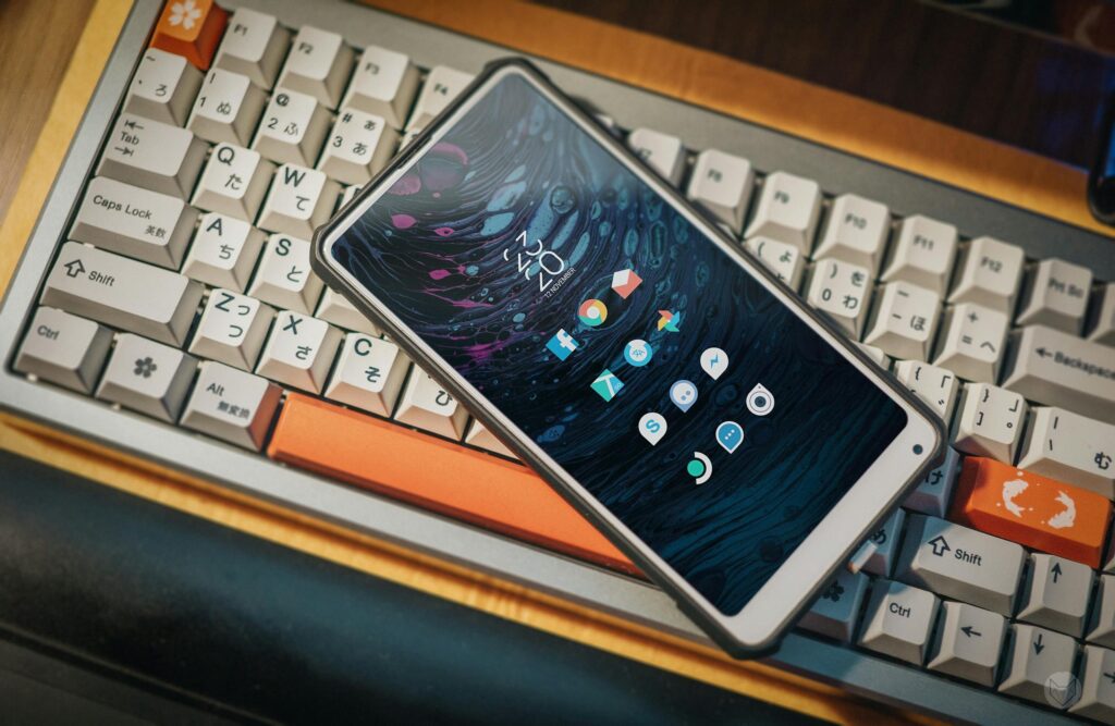 現在の画像: Close-up of a smartphone lying on a vintage mechanical keyboard, showcasing a modern interface.