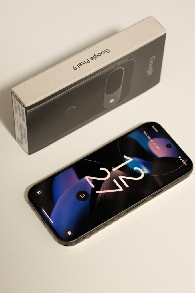 現在の画像: Close-up of Google Pixel 9 smartphone with the original packaging box, showcasing sleek design.
