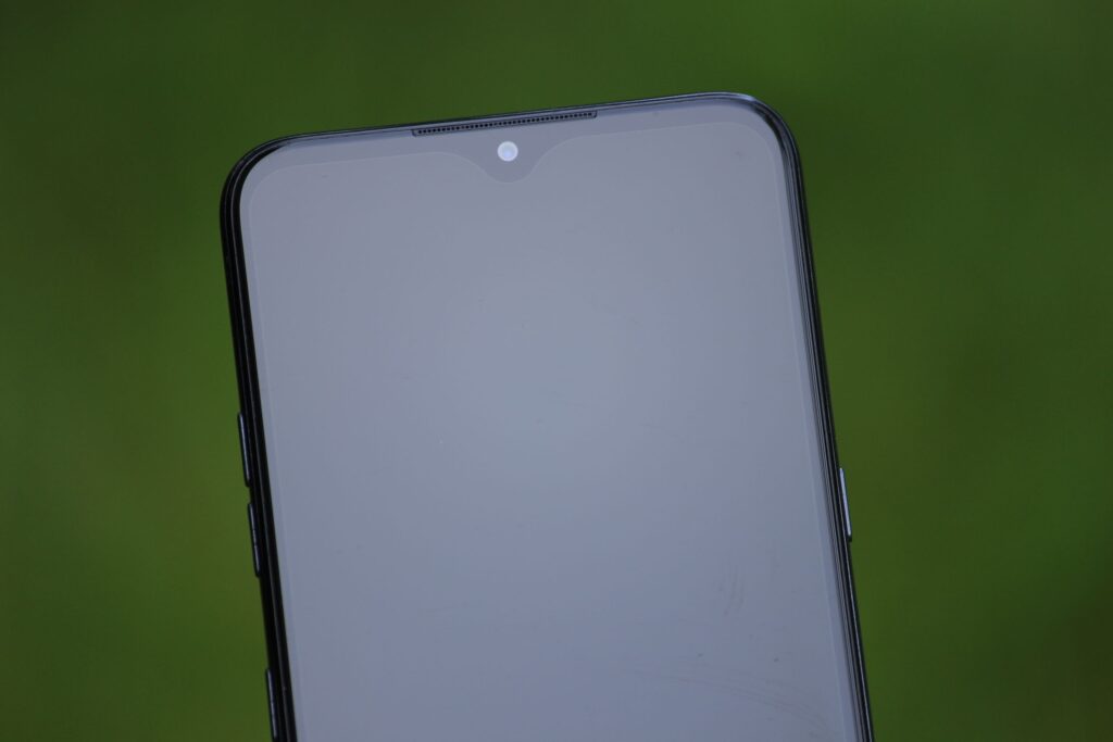 現在の画像: Close-up shot of a new smartphone with a blank reflective screen outdoors.