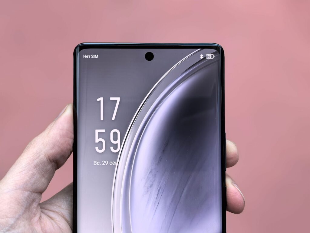 現在の画像: Close-up shot of a smartphone display showing time and reflection in a hand's grip.