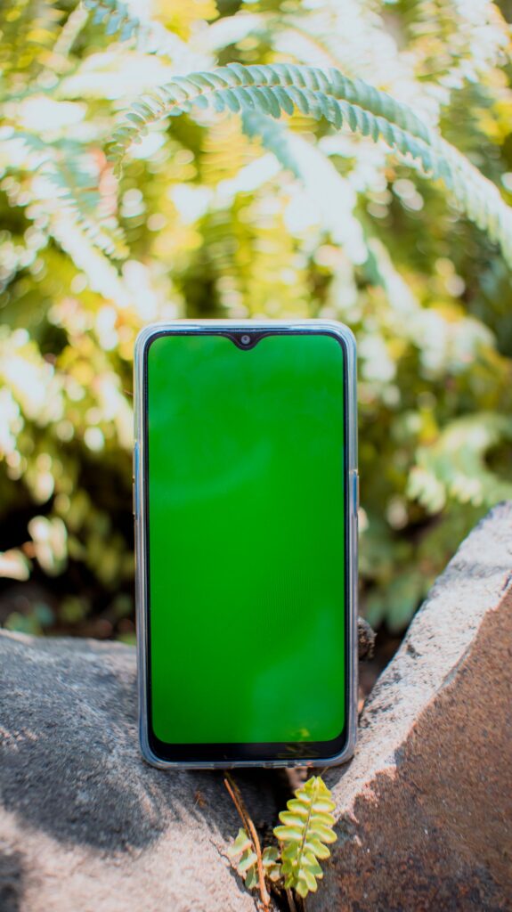 現在の画像: Convenient modern mobile phone with green chromakey on empty screen placed on rough stones on blurred background