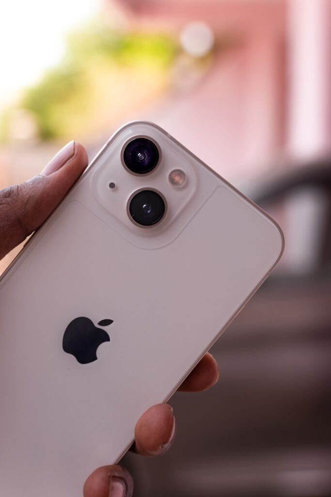 現在の画像: Detailed view of a hand holding a sleek modern smartphone with visible dual cameras.