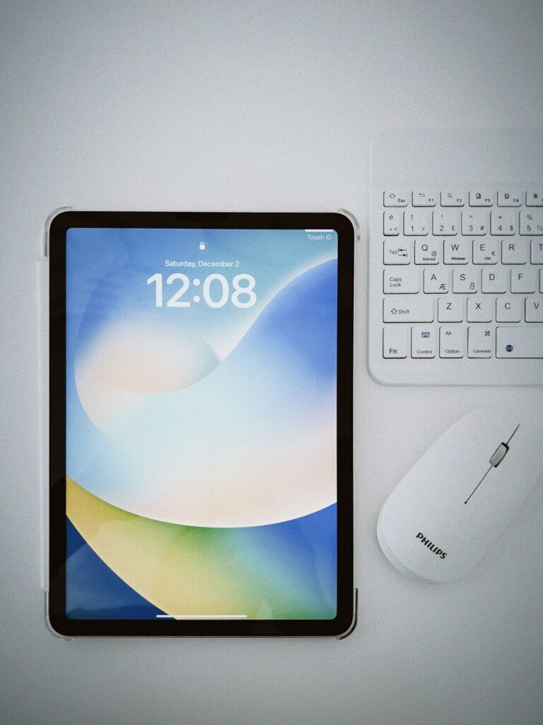 現在の画像: Flat lay of a modern tablet, keyboard, and mouse on a clean white desk.
