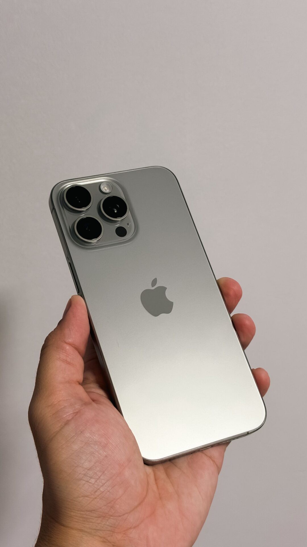 Hand holding a sleek, silver smartphone with multiple rear cameras in focus.