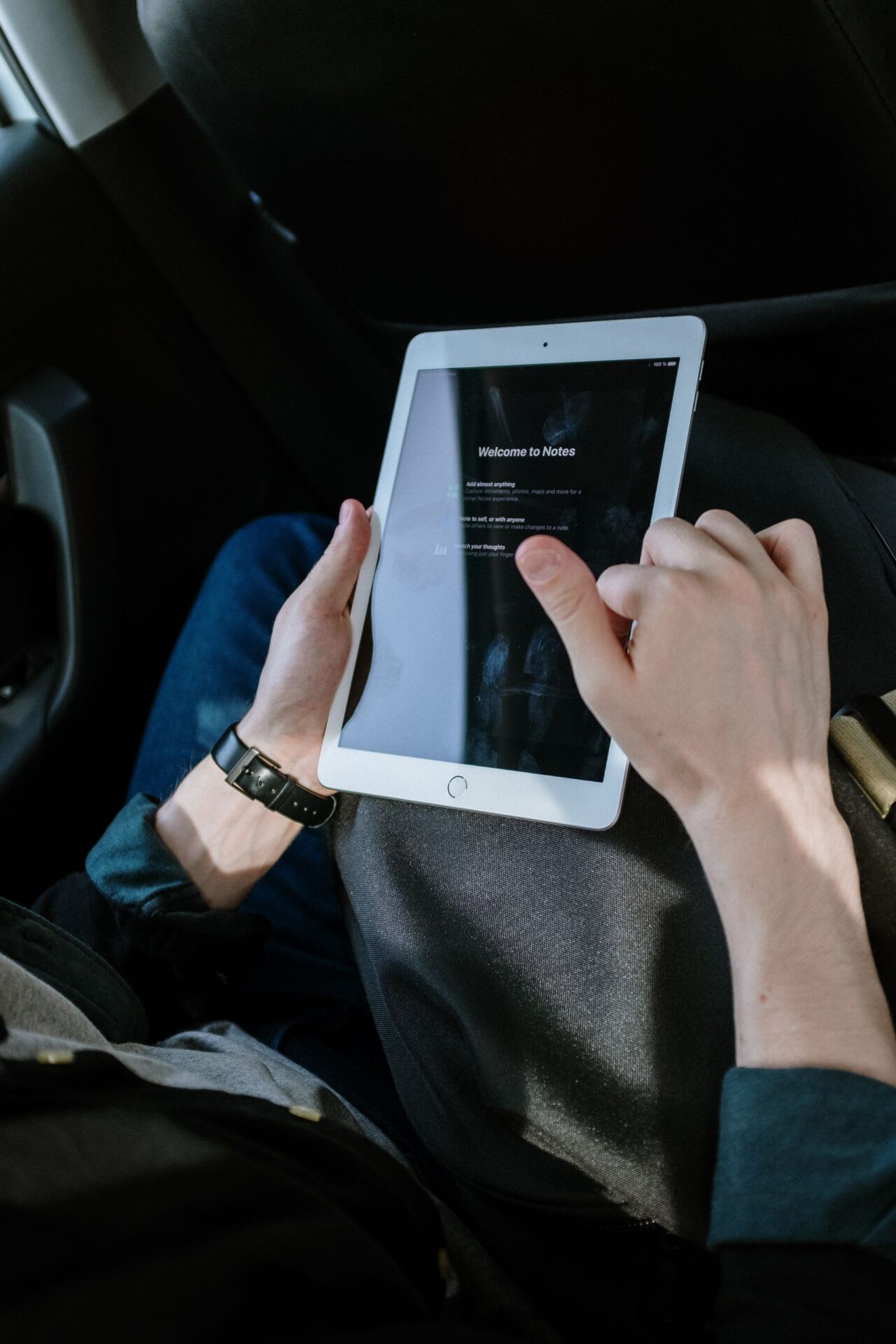 Male passenger using a tablet inside a vehicle for navigation or entertainment.