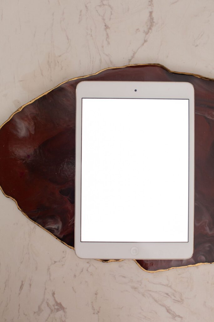 現在の画像: Minimalist overhead view of a tablet mockup on a marble surface for design presentations.