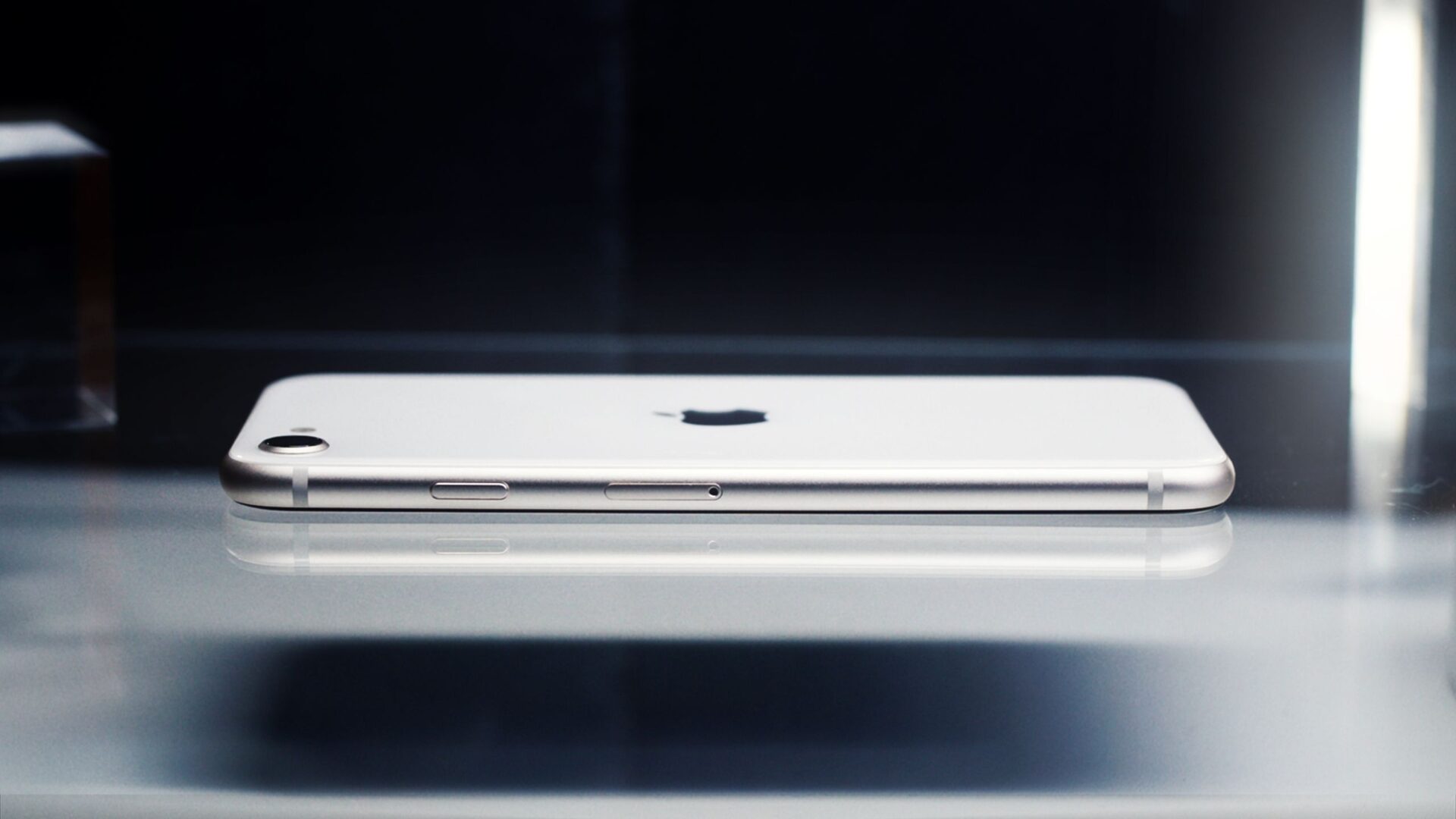 Side view of a sleek smartphone showcasing minimalist design on a reflective surface.