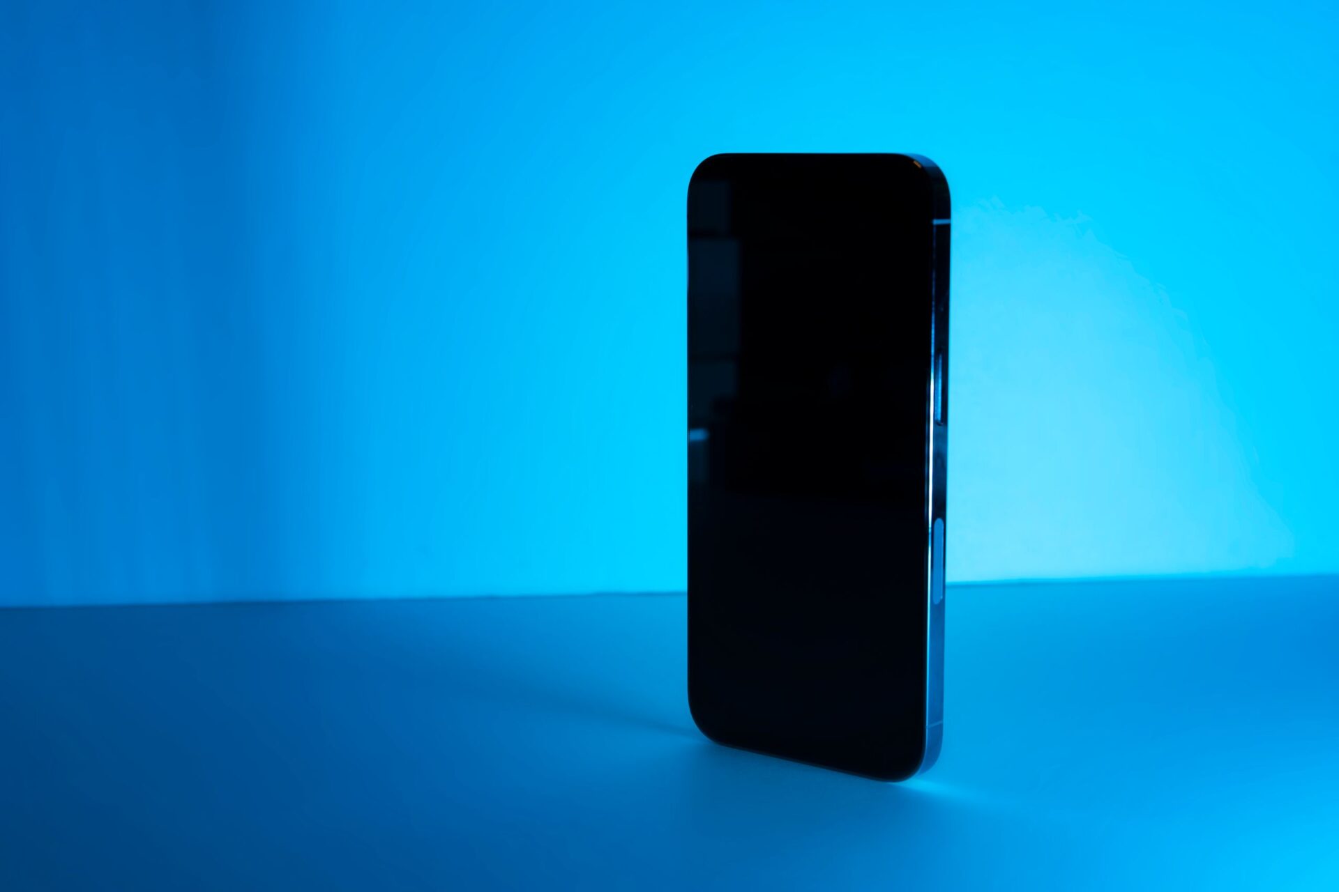 Sleek smartphone standing upright against a vibrant blue background, showcasing modern technology.