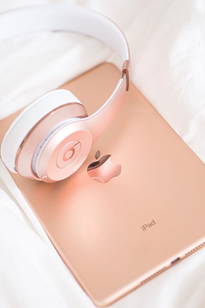 現在の画像: Stylish rose gold headphones resting on an iPad, a modern tech accessory display.